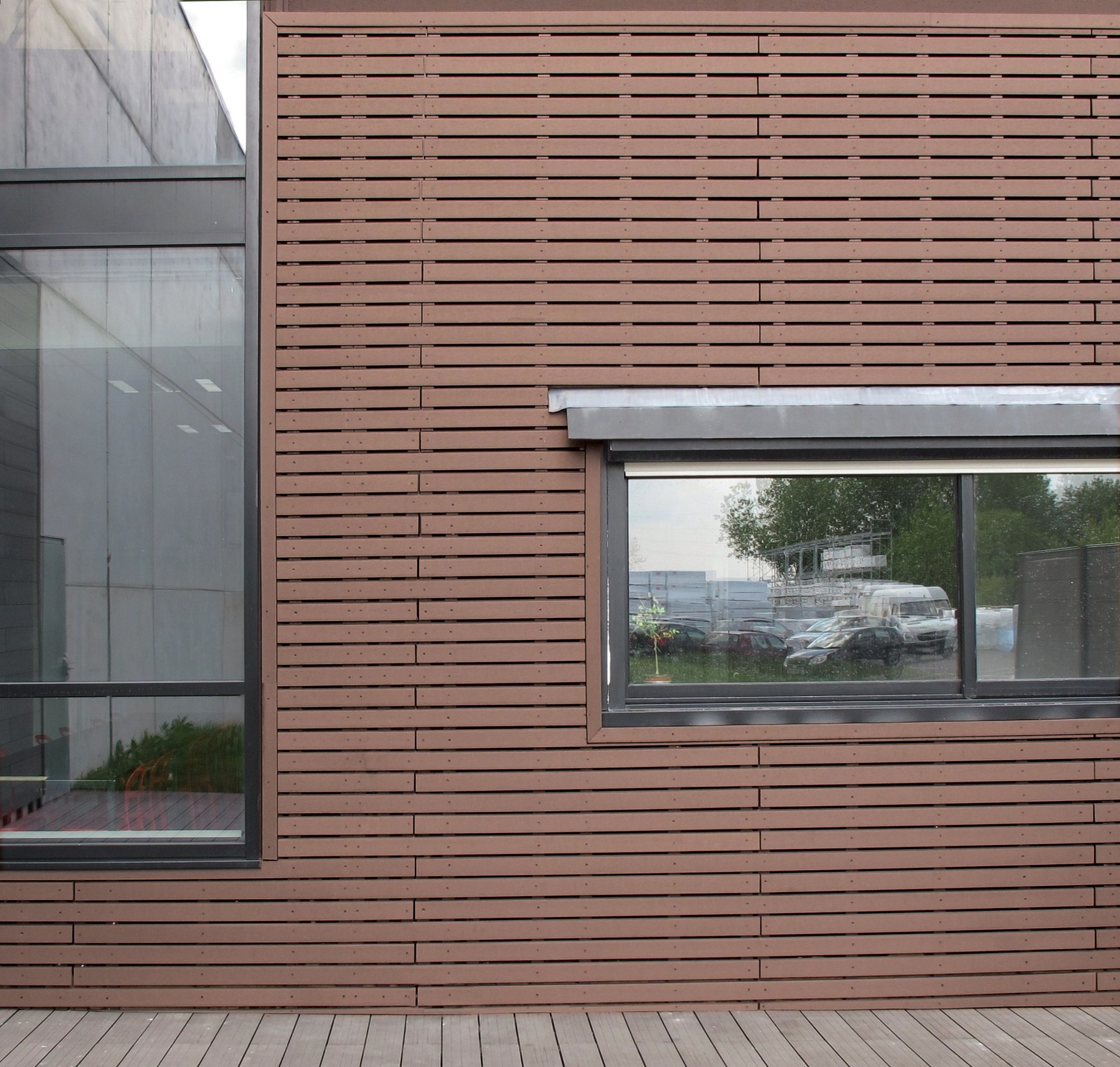 Façade en bardage ajouré redwood avec fenêtre vitrée et terrasse bois