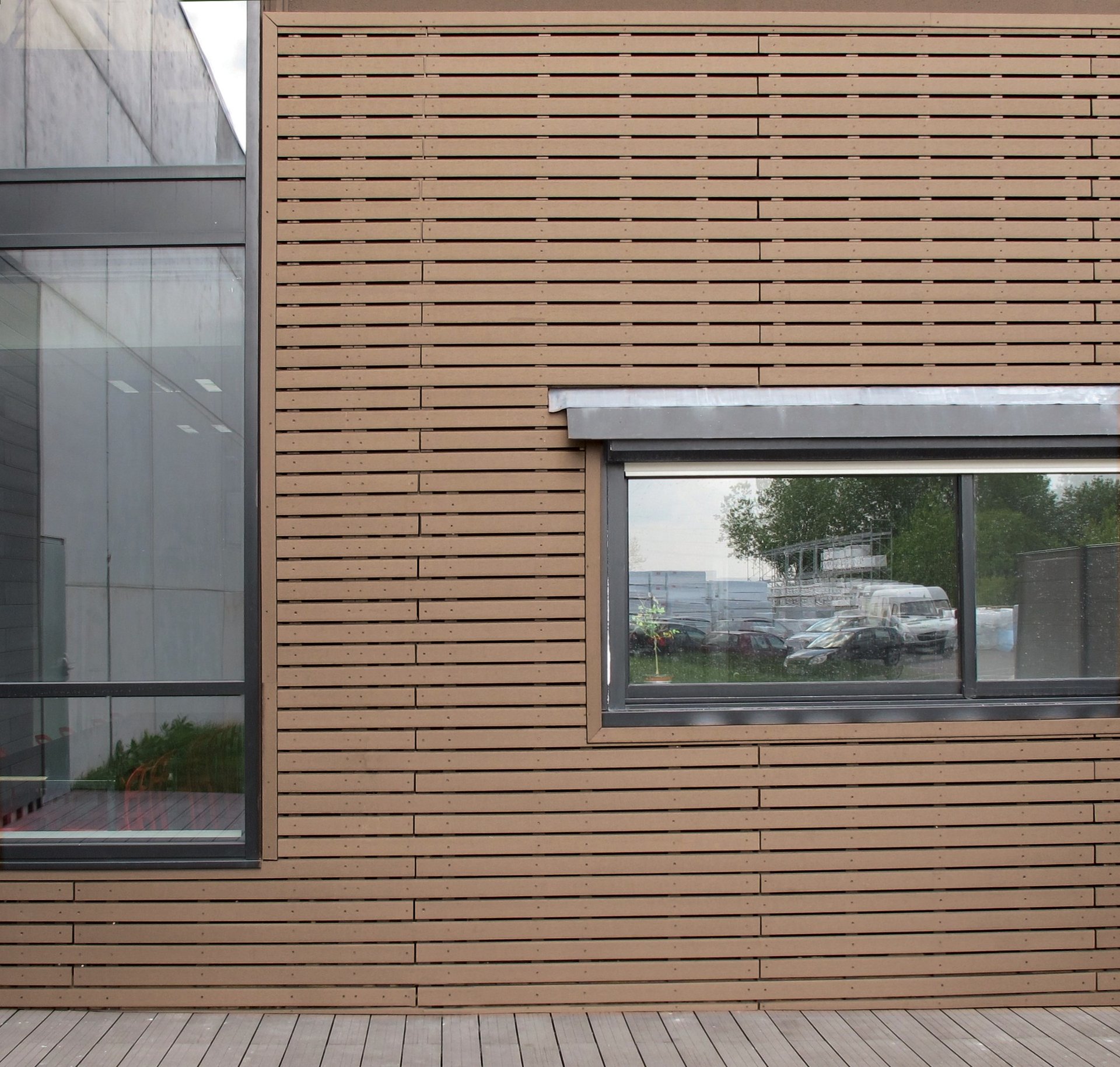 Façade en bardage ajouré teck avec fenêtre vitrée et terrasse bois