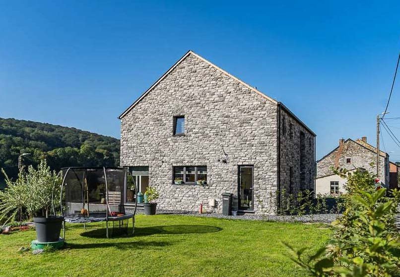 photo d'une maison sur fond de ciel bleu, dont les quatre murs sont décorés par un parement berna