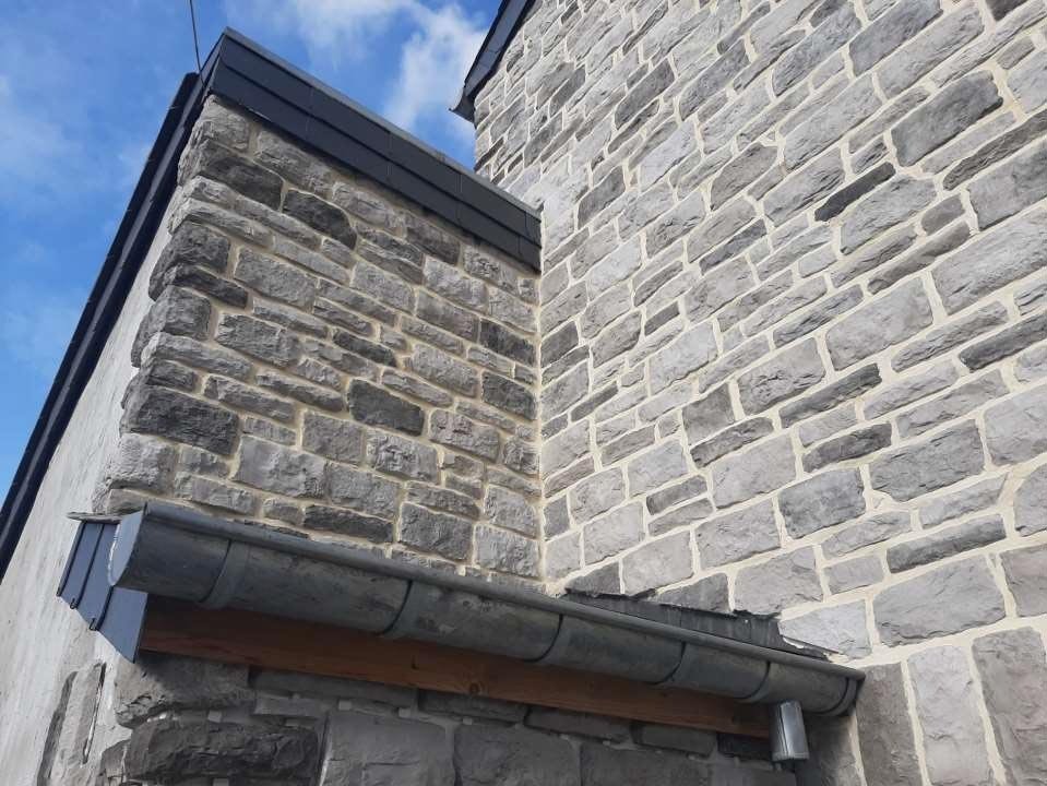 photo de deux murs d'une maison en contre plongée, montrant un parement mural piamonte cendre