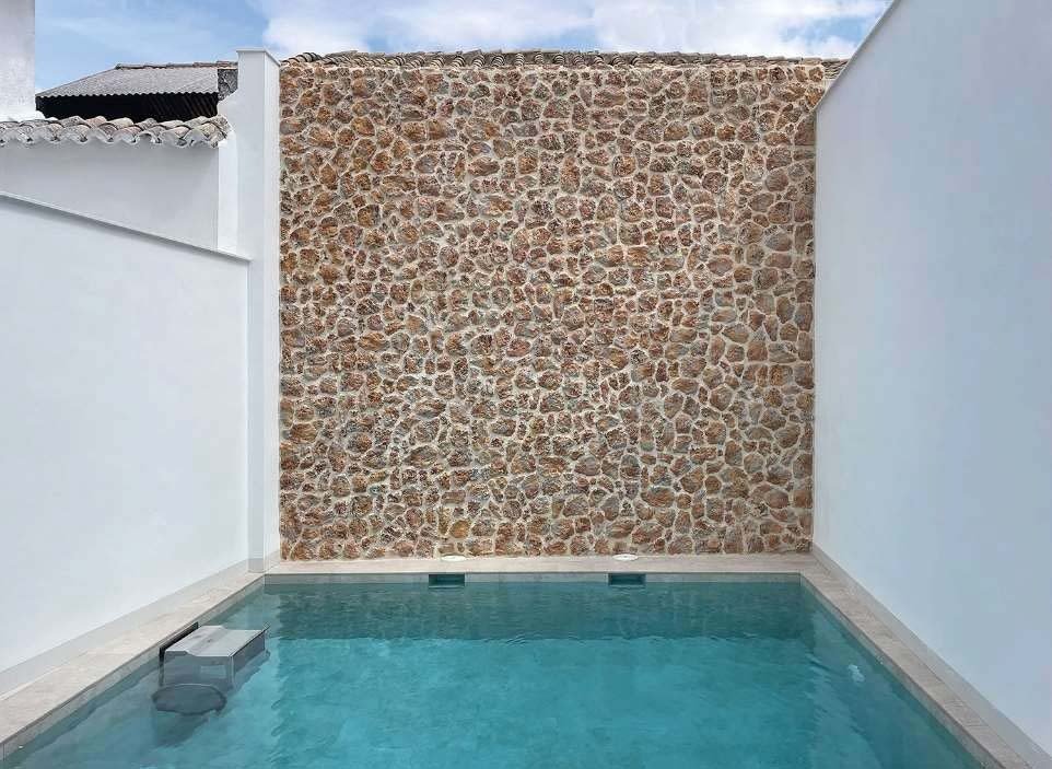 photo d'ambiance d'un mur habillé par un parement mural Timanfaya meulière au dessus d'une piscine